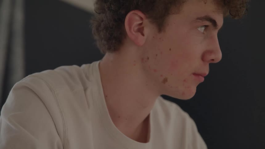 Young man sitting looks attentively to the side with a serious expression