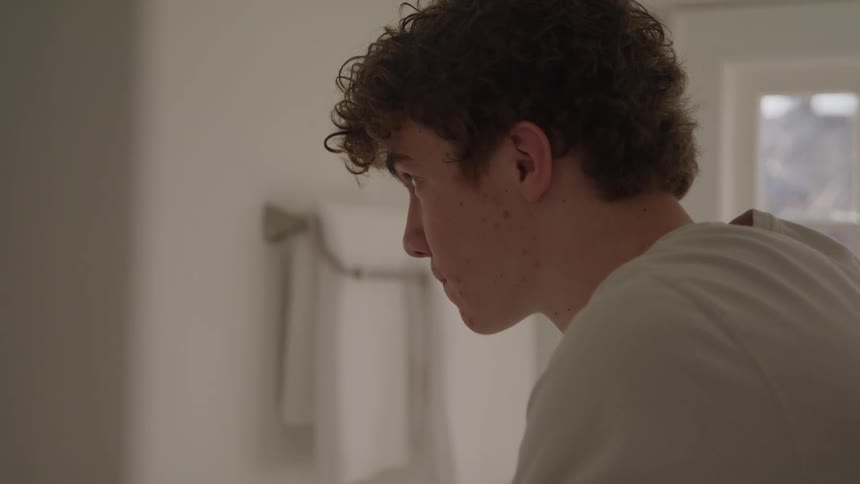 Man staring into the mirror in a bright bathroom