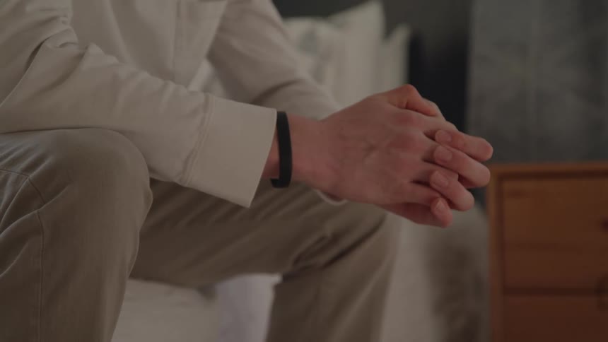 Person sitting intertwines their hands in a thoughtful gesture