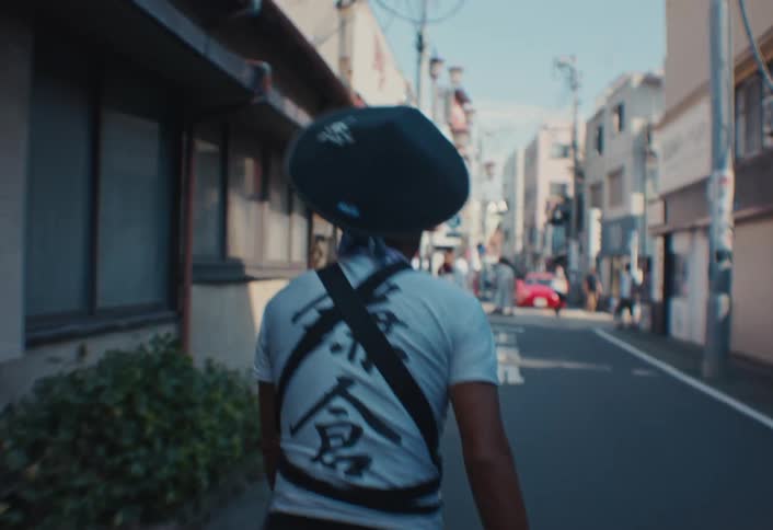 Person riding a bicycle wearing a shirt with japanese characters on an urban street
