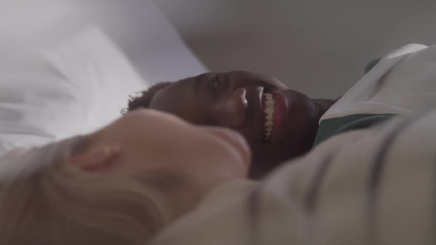 Couple lying in bed sharing looks and smiles