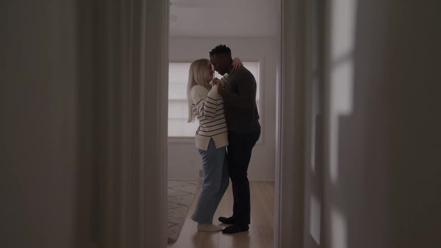 Couple dances together in a bright room touching foreheads in an intimate moment