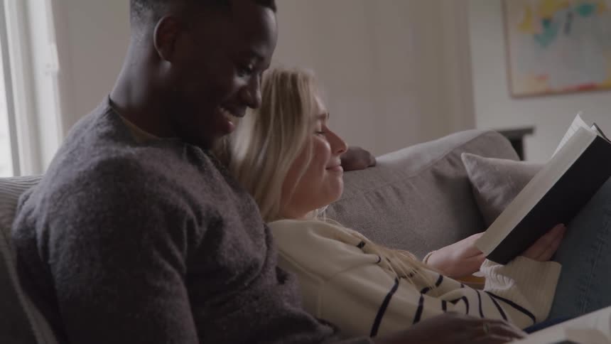 Couple shares a cozy moment reading together in a softly lit peaceful setting