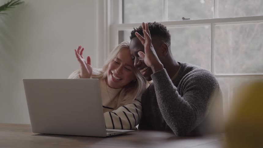 The man and woman smile and wave at the laptop