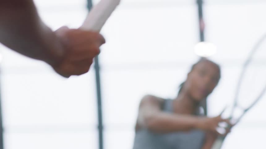 Close up of a young black female athlete practising with a tennis racket indoors in front of a mirror