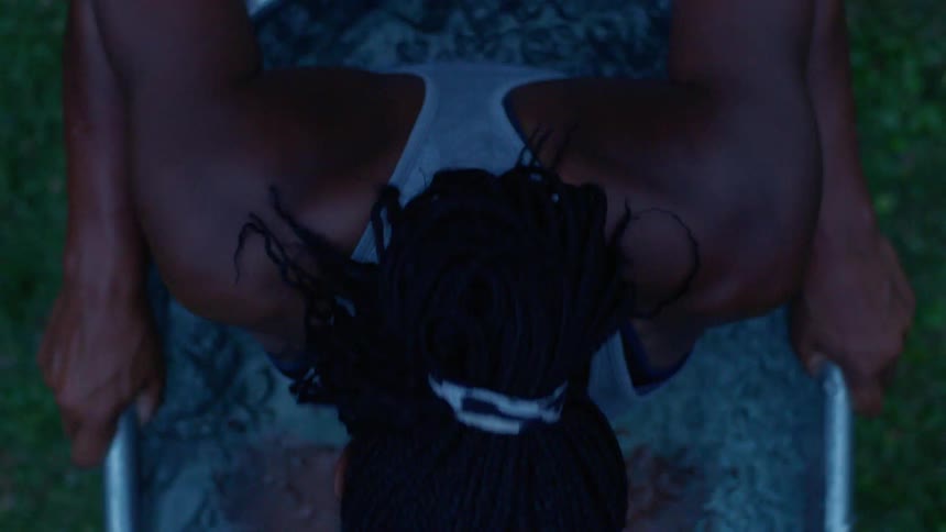 A young black woman dips her body in and out of an ice bath outdoors during daytime