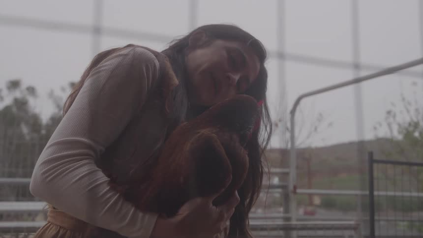 The woman is hugging a chicken