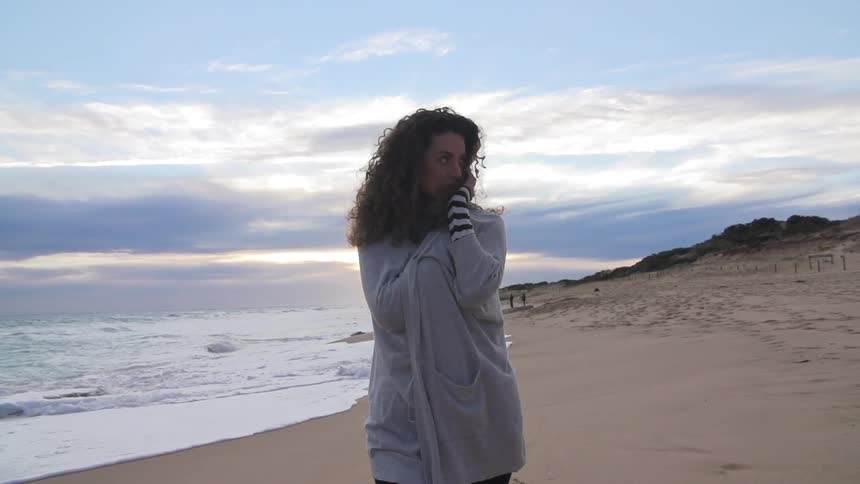 Woman walking across a beach as the sun rises