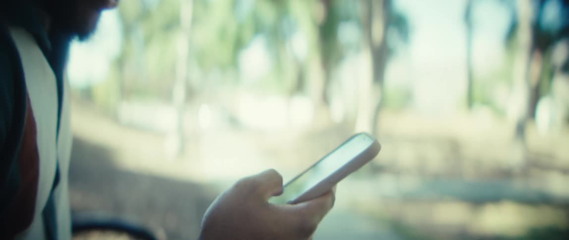 A man uses a smartphone while sitting outdoors in a park