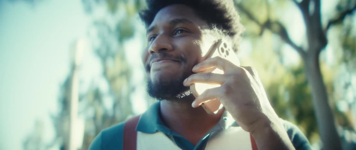 Man smiles while talking on the phone outdoors