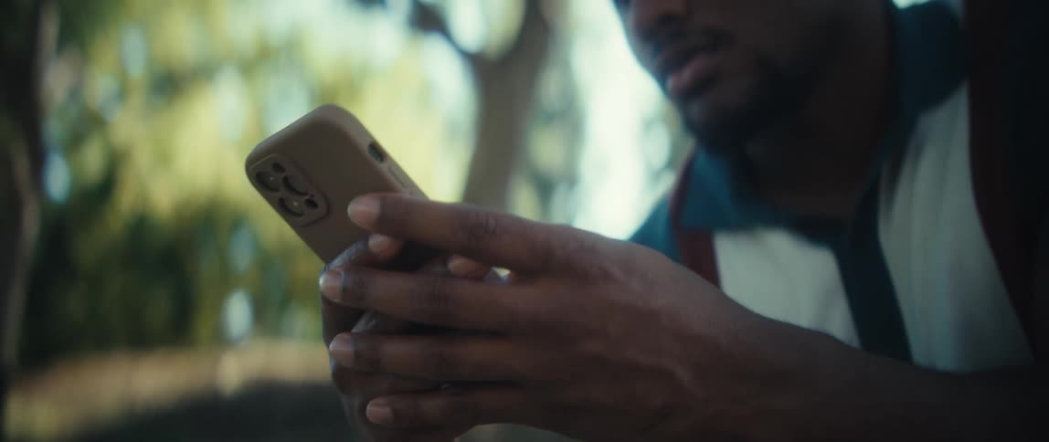 Man holds the phone with both hands while looking at the screen attentively