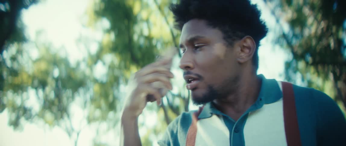 A man talks on a phone on a suburban street outdoors