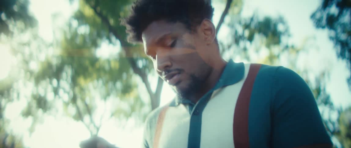 A young black man walks outside while texting on his smart phone