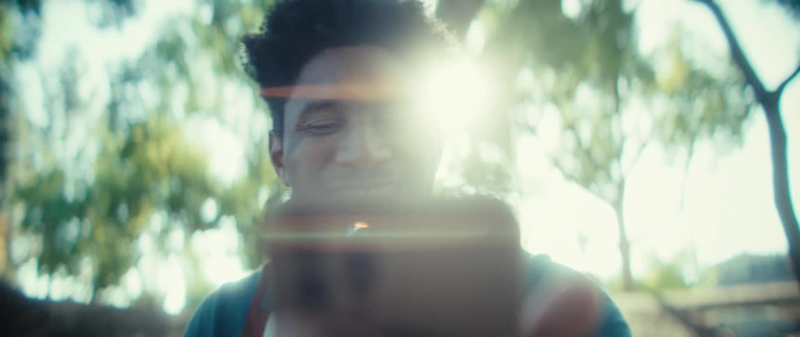 A man waves while holding his phone for a video call outside