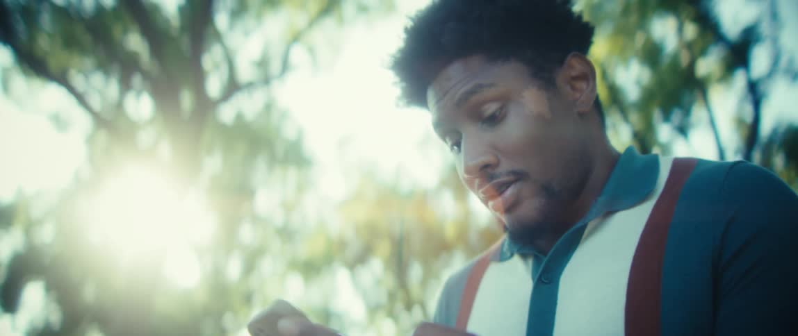 Man smiling while using his phone outdoors