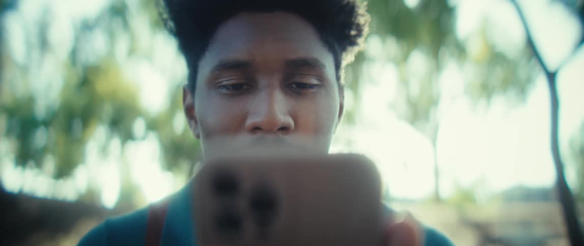 Close up of a young black man using a mobile phone while sitting outdoors during daytime
