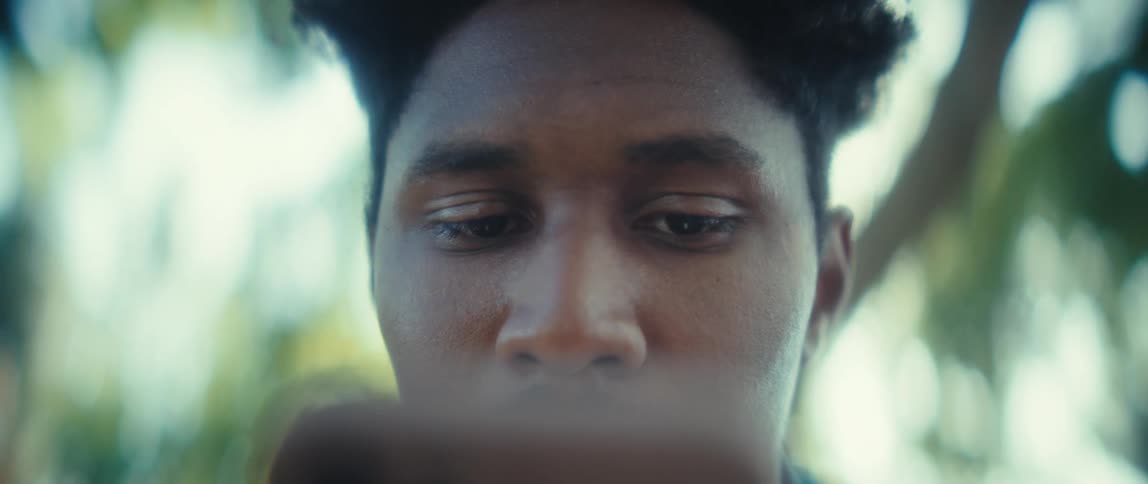 Close up of a young black man using an electronic device outdoors during daytime