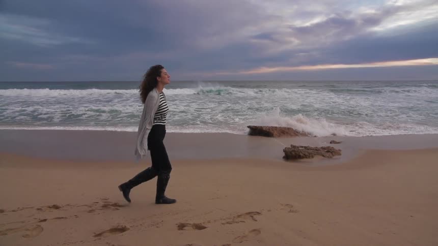 Woman walking on the beach on a cloudy day