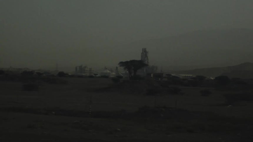 A wide shot captures a large industrial facility at dusk