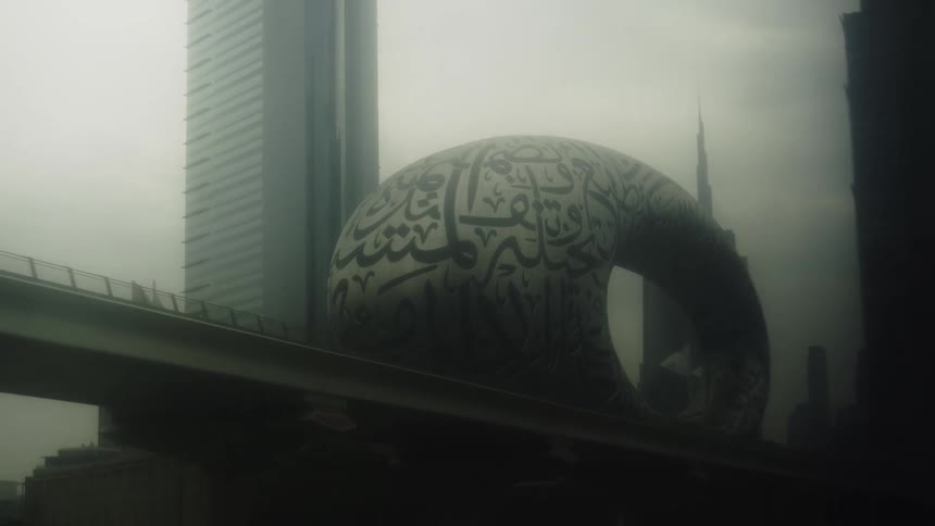 Covered in arabic calligraphy is dubais museum of the future with the burj khalifa silhouetted in the background and an elevated track in the foreground