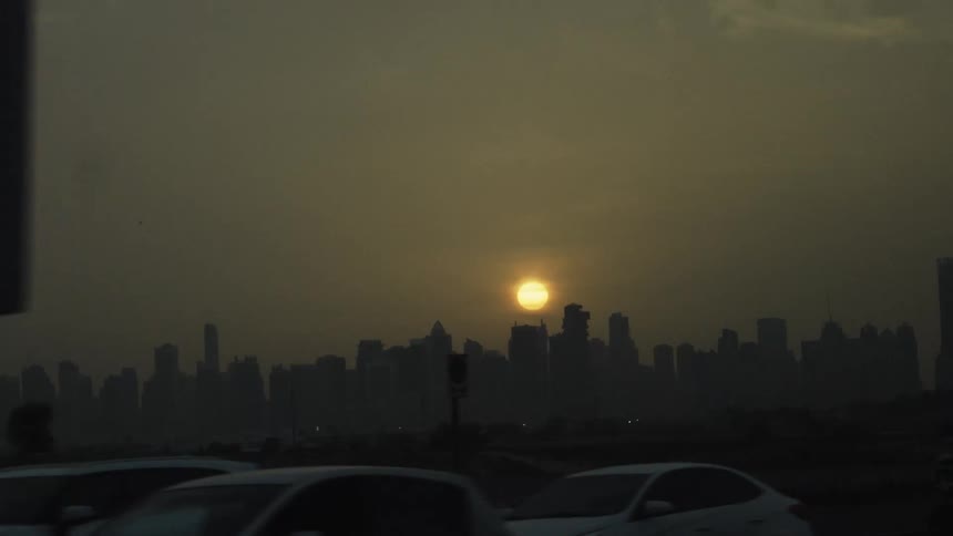 Urban traffic in the foreground with the sunset over the city skyline
