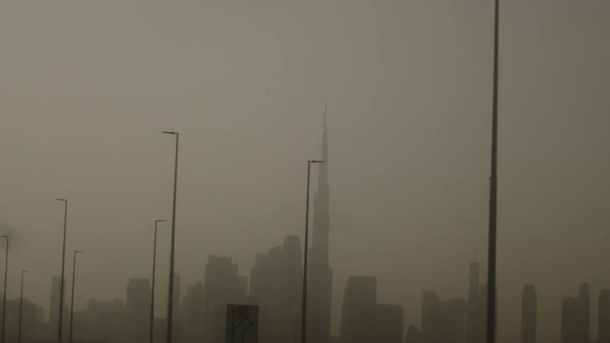 Skyscrapers emerging under a cloudy sky with lampposts in the foreground
