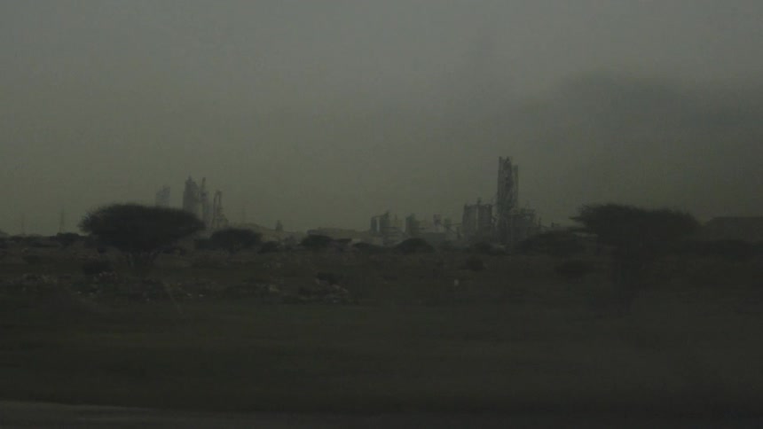 Foggy landscape reveals industrial structures in the background under a gray sky