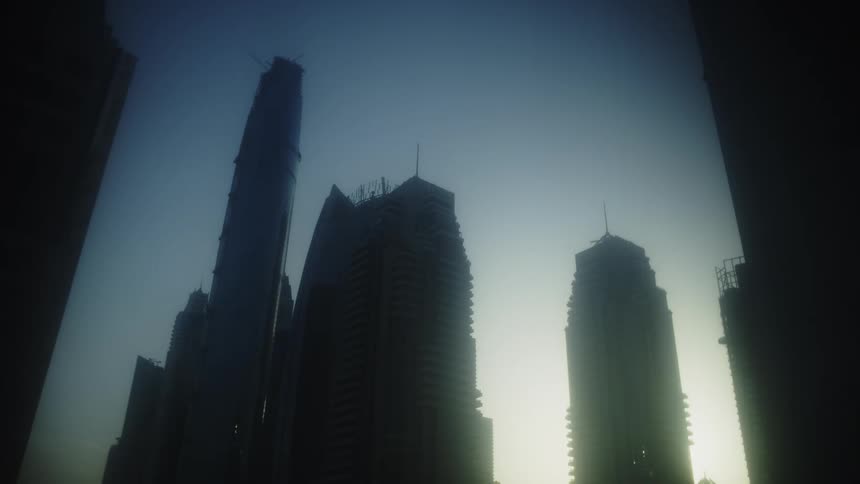Tall buildings stand out against lit sky with structure under construction on the left