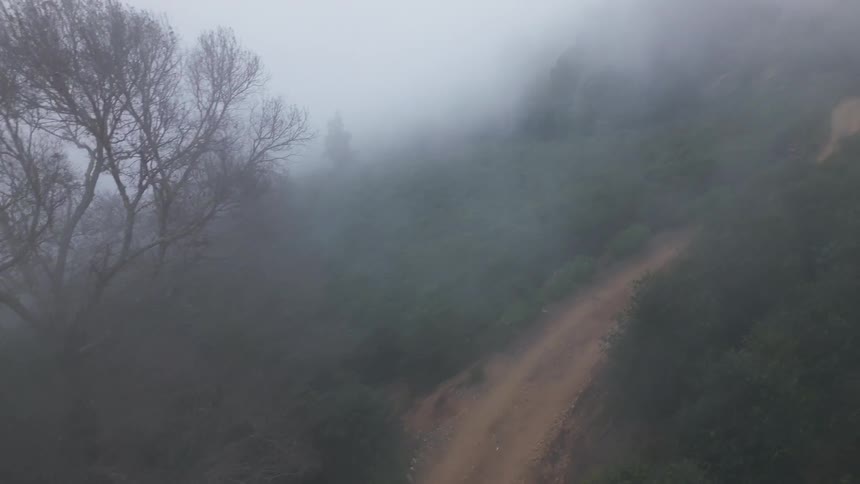 Winding dirt trail cuts through a landscape covered in fog