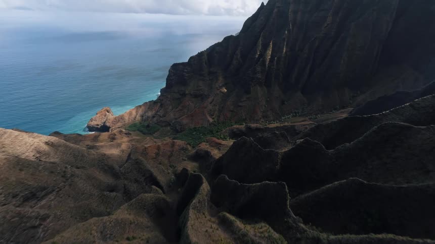 Aerial view of rugged coastal mountains above blue ocean