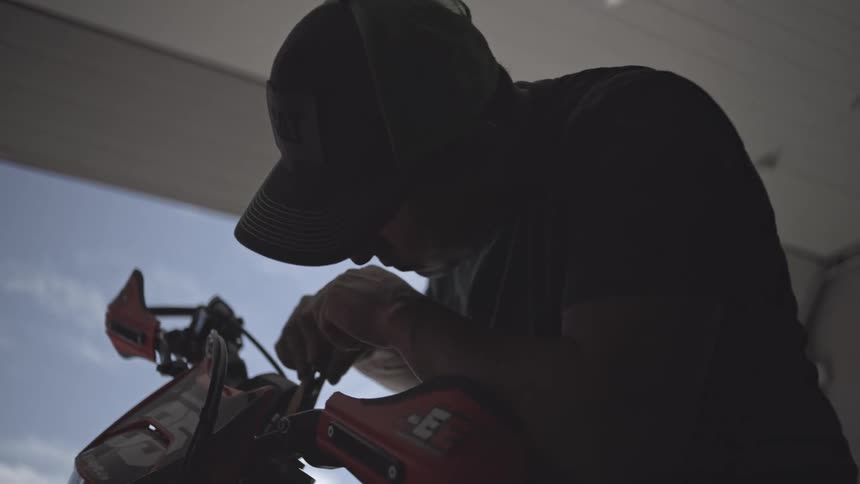 Person adjusts details of a motorcycle under daylight