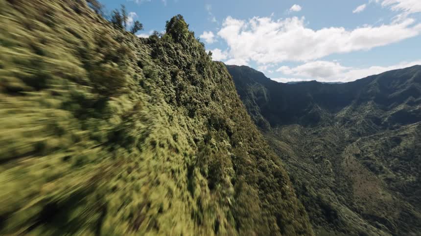 Aerial view of lush green jagged mountains under bright sky