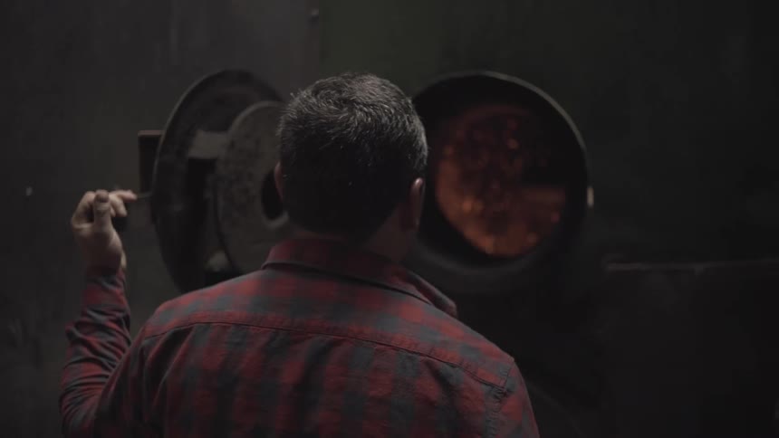 Man observes the glowing interior of a furnace in operation