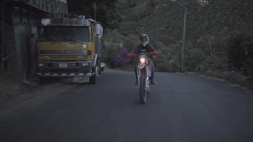 Motorcyclist riding on a narrow road surrounded by vegetation