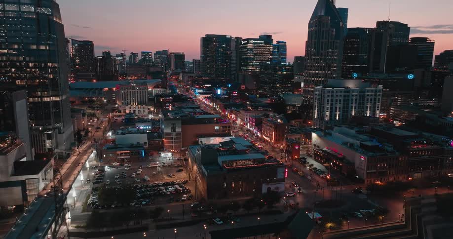 Traffic moves along downtown city streets near the waterfront at night while red tints the sky