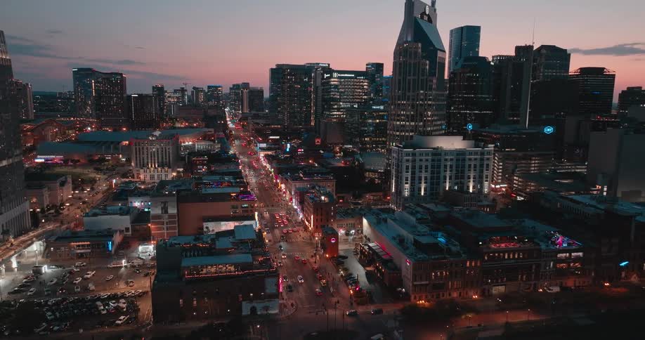 Aerial view of a brightly lit city skyline at dusk beside a river