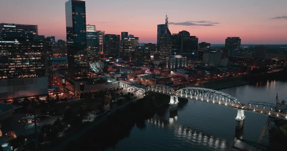 Illuminated urban panorama at dusk with a metal bridge over the river