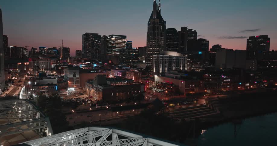 Illuminated bridge over the river leading to the urban center at nightfall