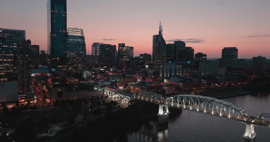 Aerial view of a city skyline with river and bridge at dusk