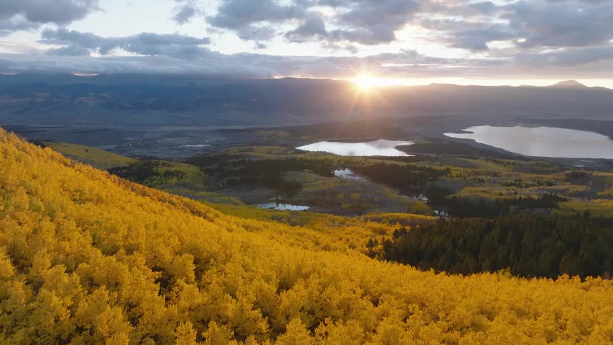 The sun is peaking out behind the mountains over the landscape