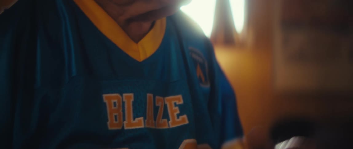 Elderly man with a focused expression wearing a blue sports jersey with yellow details
