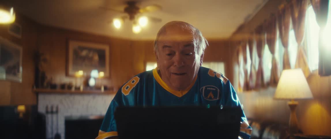 Vibrant elderly man in a sports shirt sitting watching on a tablet