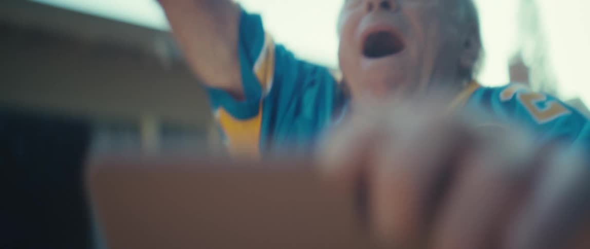 Elderly man celebrating with his arm raised while standing outdoors