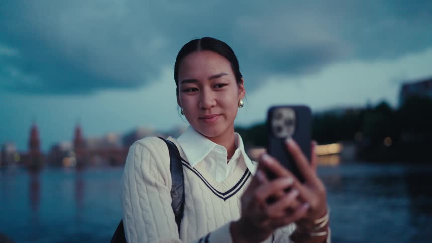 Woman taking a selfie at dusk near a body of water