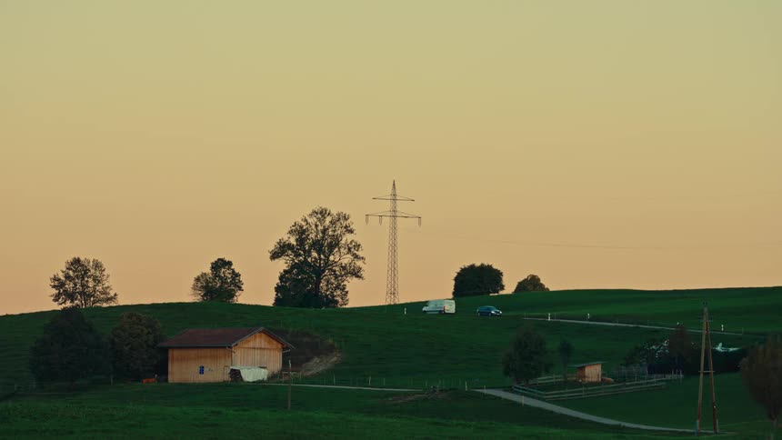 The two vehicles drive on the small road on the green hills