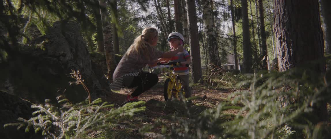 Young woman putting a helmet on her toddler before he rides his bike.