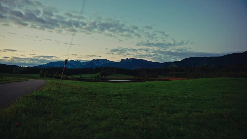 A wide grassland stretches across the landscape glowing in the warm light of the setting sun