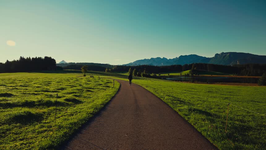 A man walking down a road in a rural area during daytime