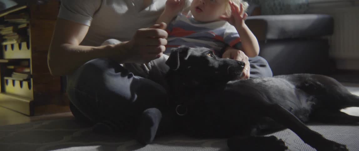 Young father and toddler boy sharing a quiet moment with the family dog.