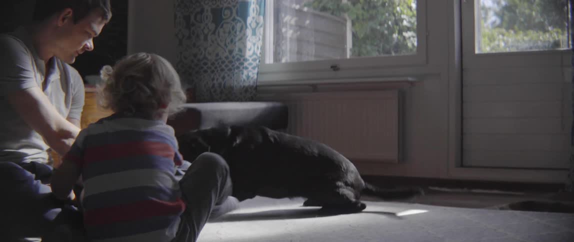 A man is playing on the floor with a toddler child and a dog